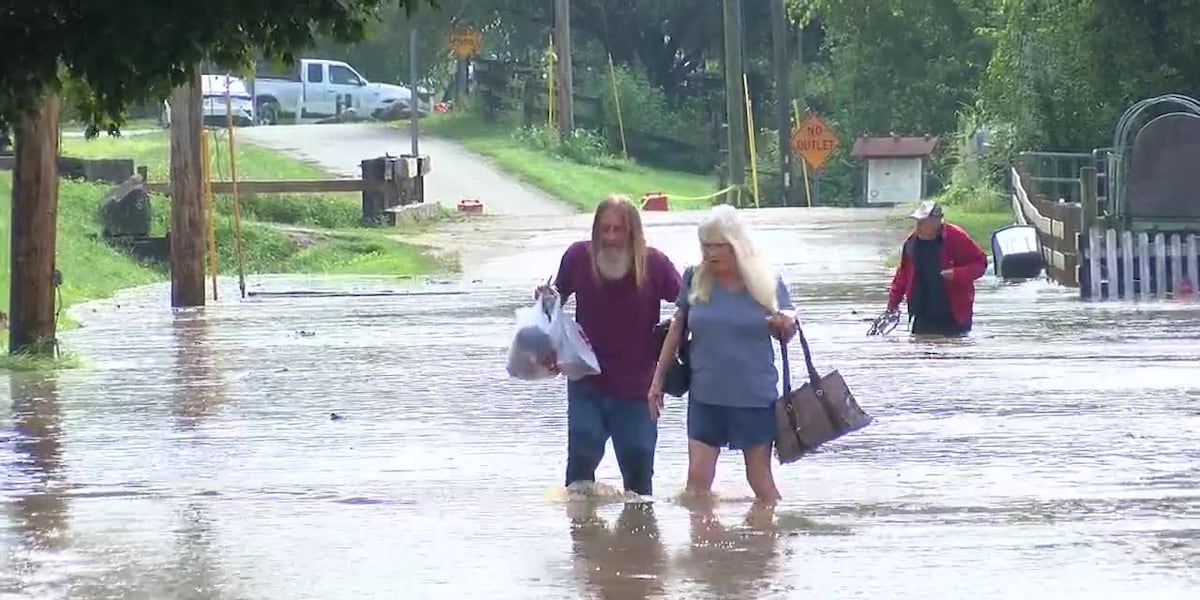 Residents carry belongings through floodwaters