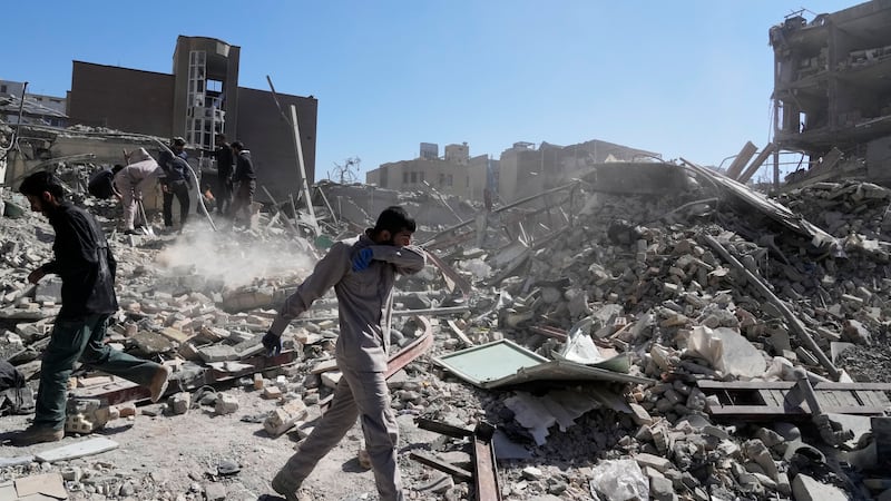 A group of men inspects the ruins of a police station struck Monday amid the U.S.–Israeli...